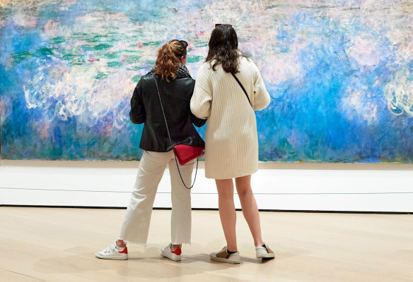 Picture of 2 young women in a museum looking at a Water Lillies painting by Monet
